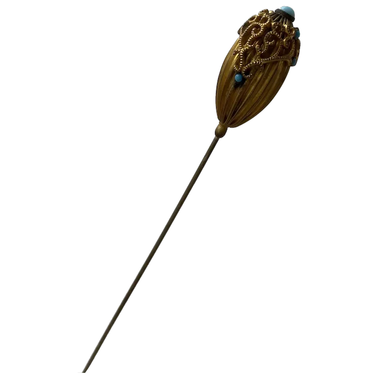 Antique gold-tone hat pin with filigree oval head and small turquoise beads on a long slender shaft.
